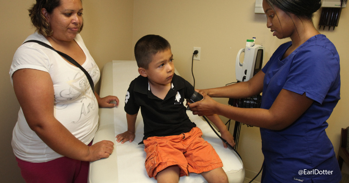 Mother watches son have blood pressure taken by clinician