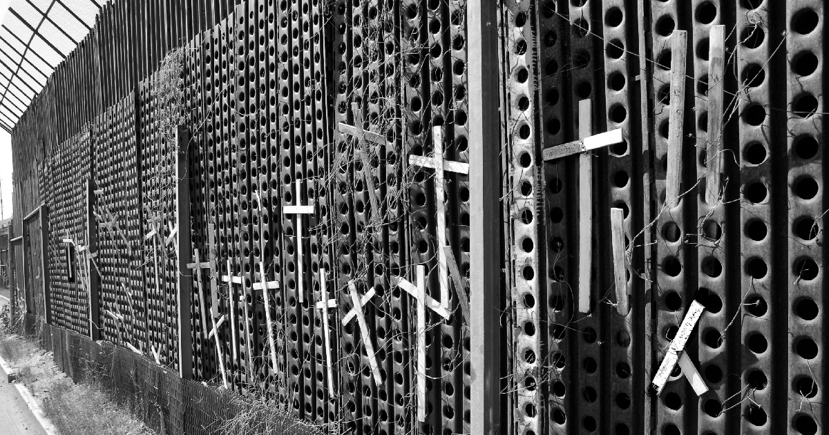 A wall on the US-Mexico border with crosses attached to it.