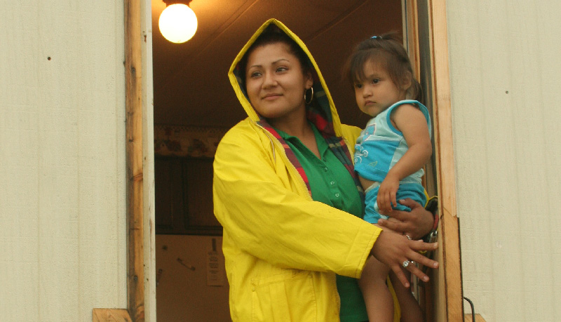 Woman stands in raincoat with young daughter