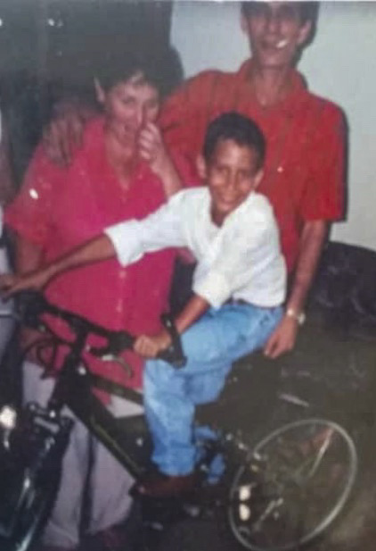 Saul Delgado as a kid posing for a photo with his parents