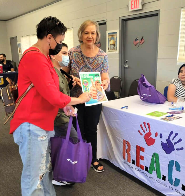 Attendees receive materials at a REACH information table.