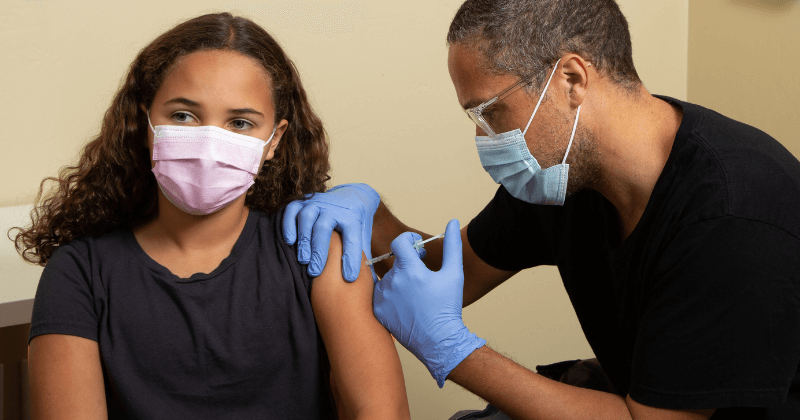 A young person is vaccinated by a clinician