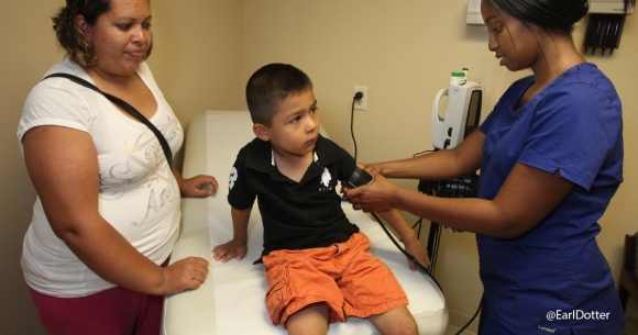 Mother watches son have blood pressure taken by clinician
