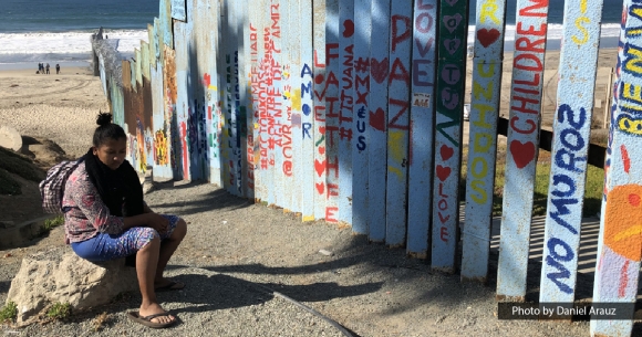 Asylum seeker sits on the Mexican side of the border