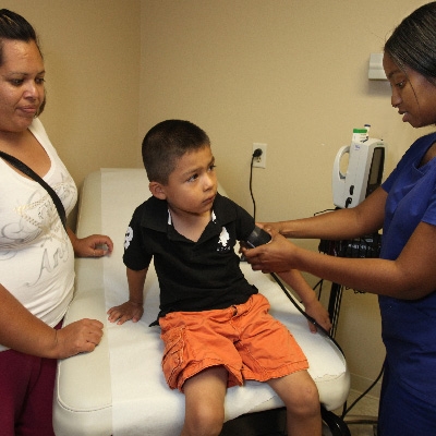 Mother watches as son has blood pressure taken by clinician