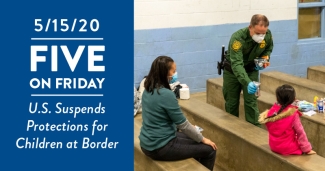 A border patrol officer hands food to a child in a detention facility