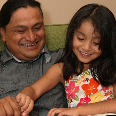 child reading book with her dad