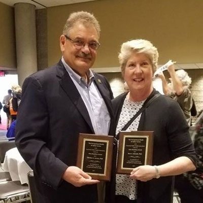 Sara Quandt y Tom Arcury sosteniendo el premio Alice Hamilton